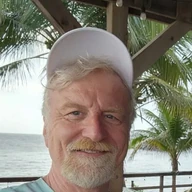 Andrew Easy Anderson, smiling in a ball cap on a beach porch.